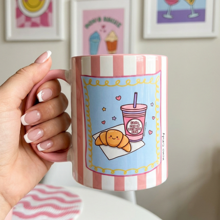 hand holding a motivational cup with a croissant on it