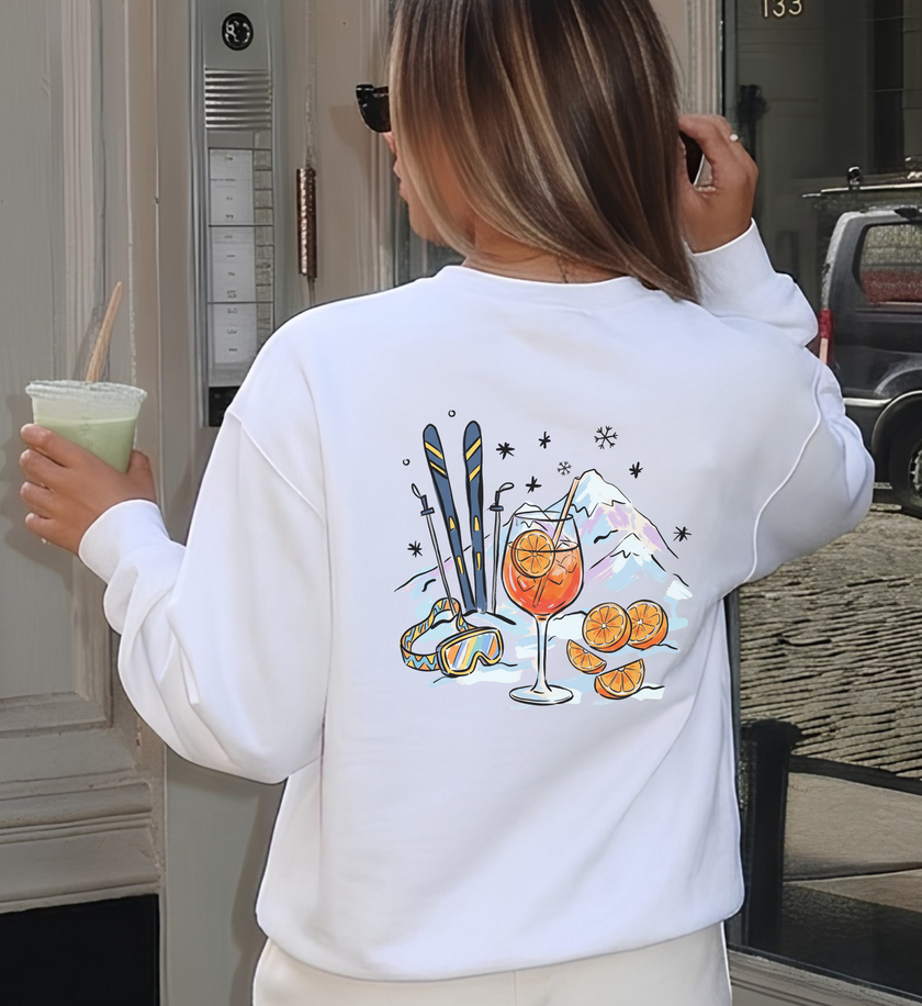 Weißes Après-Ski-Sweatshirt in Rückansicht mit Spritz-Glas, Orangen, Skiern, Skibrille und gezeichneten Bergen.
