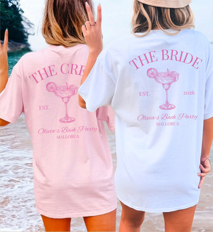 Zwei Frauen am Strand in personalisierten JGA-Shirts von Cincerely Yours mit Margarita-Motiv: Ein weißes 'The Bride' Shirt und ein rosa 'The Crew' Shirt für eine Bachelorette Party auf Mallorca.