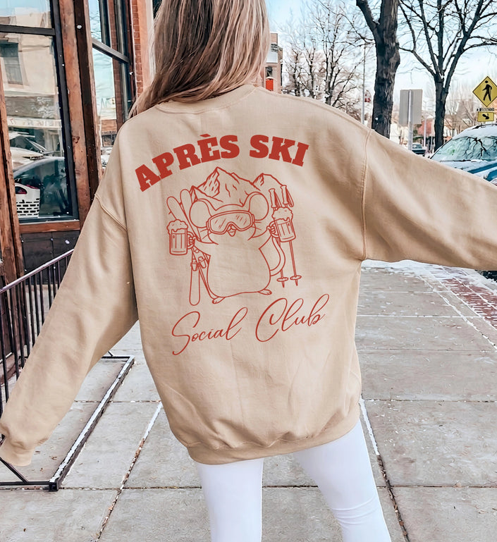 Rückansicht eines beigen Cincerely Yours Sweatshirts mit rotem Backprint, zeigt eine illustrierte Maus mit Skibrille, Skiern und Cocktailgläsern, Motiv Apres Ski Social Club.