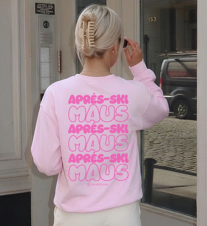 Nahaufnahme der Rückseite eines pastellrosa Cincerely Yours Sweatshirts mit prominentem Apres Ski Maus Backprint in kräftiger pinker Bubble-Schrift, getragen mit einer Haarspange.