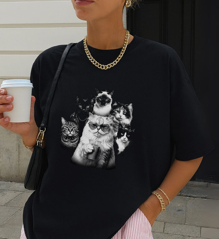Schwarzes Cincerely Yours T-Shirt mit detailreichem Bootleg-Katzen-Grafikprint, eine Katze mit Herzbrille hält einen Sommerdrink, lässiger Streetstyle, Fokus auf T-Shirt-Schnitt und hochwertigem Motivdruck.
