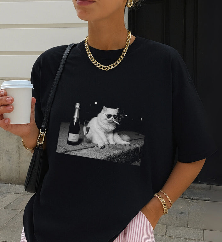 Modisches schwarzes T-Shirt mit markantem Cat-Print, dazu goldene Kette und Accessoires, lässig im Alltag gestylt mit Fokus auf das lustige Katzen-Grafikdesign.