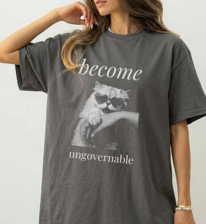 Frontansicht eines grauen Oversized-T-Shirts mit dem Aufdruck 'become ungovernable' und einer Katze mit Herz-Sonnenbrille als vintage Bootleg-Print auf der Vorderseite.