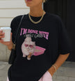 Schwarzes Cincerely Yours Oversized T-Shirt mit frechem Katzen-Design, Herzbrille und Kaffee, modisch gestylt mit goldener Kette und Streifenshorts.