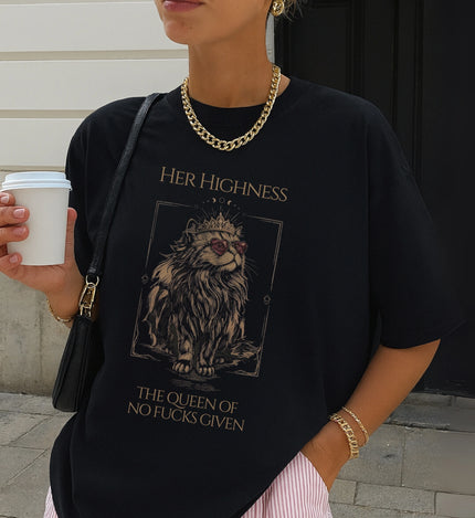 Urbanes Lifestyle-Foto: Person trägt schwarzes T-Shirt mit detailliertem Katzen-Print, kombiniert mit goldener Kette und Tasche vor einer weißen Wand.