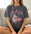 Dunkelgraues Cincerely Yours Vintage-Look T-Shirt mit humorvollem Katzen-Grafikaufdruck, Herzsonnenbrille und Kaffeepause, lässig sitzend auf einem Sofa.