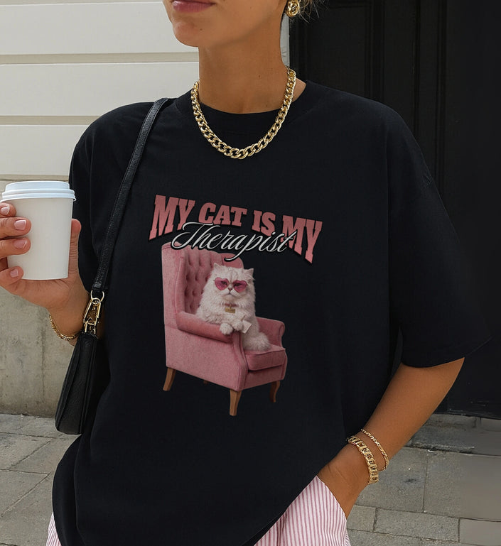 Schwarzes Cincerely Yours Statement-Shirt mit auffälligem Katzen-Grafikprint. Das Design zeigt eine Katze mit Herzsonnenbrille, modern kombiniert mit Goldkette.