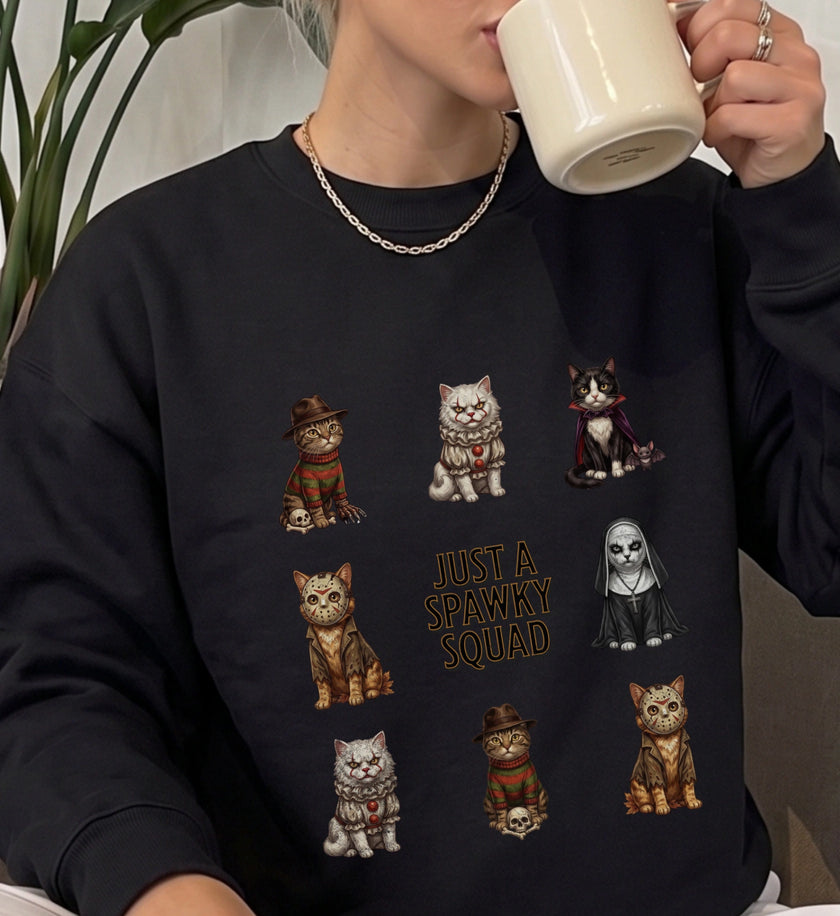 Eine Person trägt ein schwarzes Cincerely Yours Sweatshirt mit Just a Spawky Squad Grafik aus gruseligen Katzen-Charakteren im Horror-Stil.