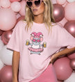 Frau in pinkem T-Shirt mit Aufdruck einer niedlichen Karnevals-Maus, die zwei Bierkrüge hält, vor einem Hintergrund aus vielen pinken und weißen Luftballons.