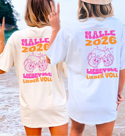 Zwei Frauen am Strand in der Rückansicht tragen das Cincerely Yours Malle 2026 Shirt in Weiß und Beige mit pink-orangefarbenem Neon Bierkrug Motiv und dem Spruch Lieber voll.