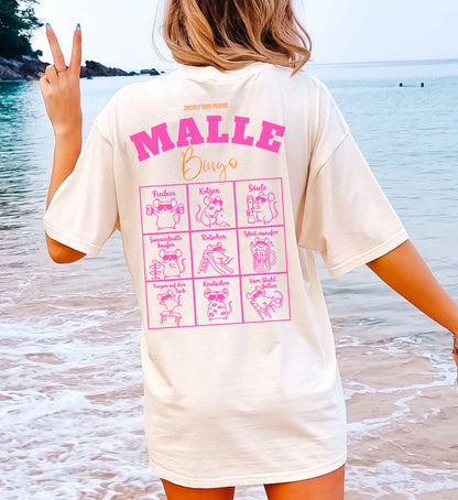 Cincerely Yours Mallemaus Shirt in Beige mit pinkem Malle Bingo Aufdruck auf dem Rücken, getragen von einer Frau am Strand – ideales Malle Party Shirt für den Urlaub.