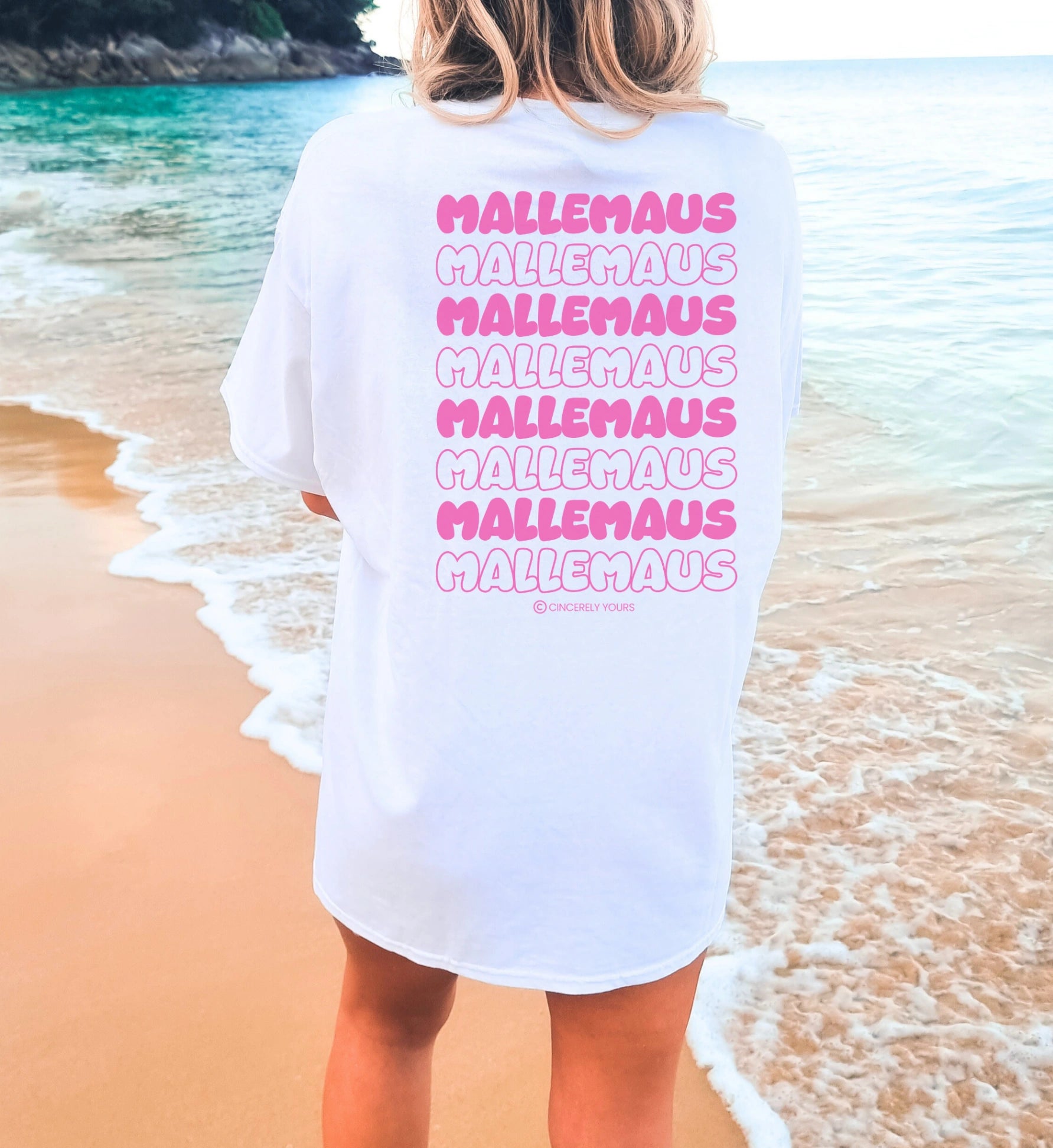 Weißes Oversize Mallemaus Shirt von Cincerely Yours mit pinkem Malle Maus T-Shirt Backprint, Motiv Mallemaus pink in der Rückenansicht am Strand.