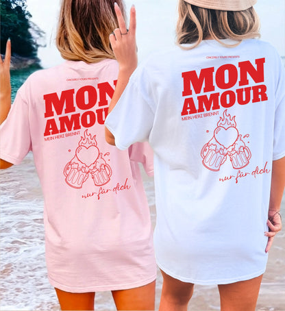 Cincerely Yours Mon Amour T-Shirt für Malle Party – Zwei Frauen am Strand in pinken und weißen Party Shirts mit Grafik 'Mein Herz brennt nur für dich', Rückansicht.