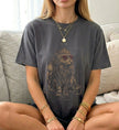 Eine Frau trägt ein graues Cincerely Yours T-Shirt mit einem mystischen Katzen-Druck, der eine Katze mit Krone und Herzbrille in einem 90er-Jahre-Bootleg-Stil zeigt.