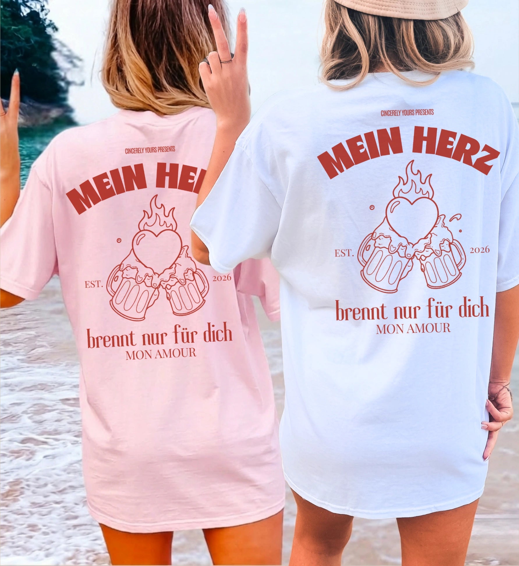 Zwei Frauen am Strand von hinten in rosa und weißen Cincerely Yours Oversized T-Shirts mit dem Rückenprint 'Mein Herz brennt nur für dich' und einer Grafik von anstoßenden Bierkrügen.