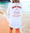 Weißes Oversized T-Shirt von Cincerely Yours mit Rückenprint 'Mein Herz brennt nur für dich', Illustration von anstoßenden Bierkrügen und Herzflamme, getragen am Strand.
