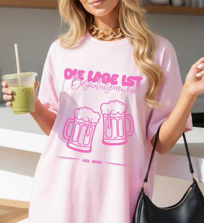 Ein rosa Oversized T-Shirt mit dem Aufdruck Die Lage ist besäufniserregend und zwei Bierkrügen in Pink, getragen von einer Frau mit Goldkette.