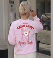 Rückansicht eines pastellrosa Cincerely Yours Sweatshirts mit rotem Aprés-Club Grafik-Print, Motiv zeigt einen lachenden Cocktail-Charakter mit Skiausrüstung im Retro-Stil.