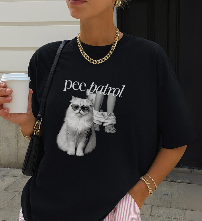 Nahaufnahme des schwarzen Pee Patrol Katze T-Shirts mit Kaffebecher und Goldkette im urbanen Streetstyle-Look.