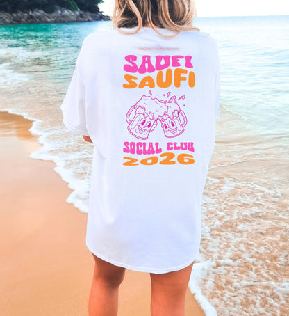 Cincerely Yours Party Shirt mit 'Saufi Saufi Social Club' Backprint und lachenden Bierkrügen in Pink und Orange, weißes Oversize T-Shirt am Strand von hinten fotografiert.