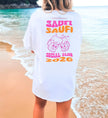 Cincerely Yours Party Shirt mit 'Saufi Saufi Social Club' Backprint und lachenden Bierkrügen in Pink und Orange, weißes Oversize T-Shirt am Strand von hinten fotografiert.