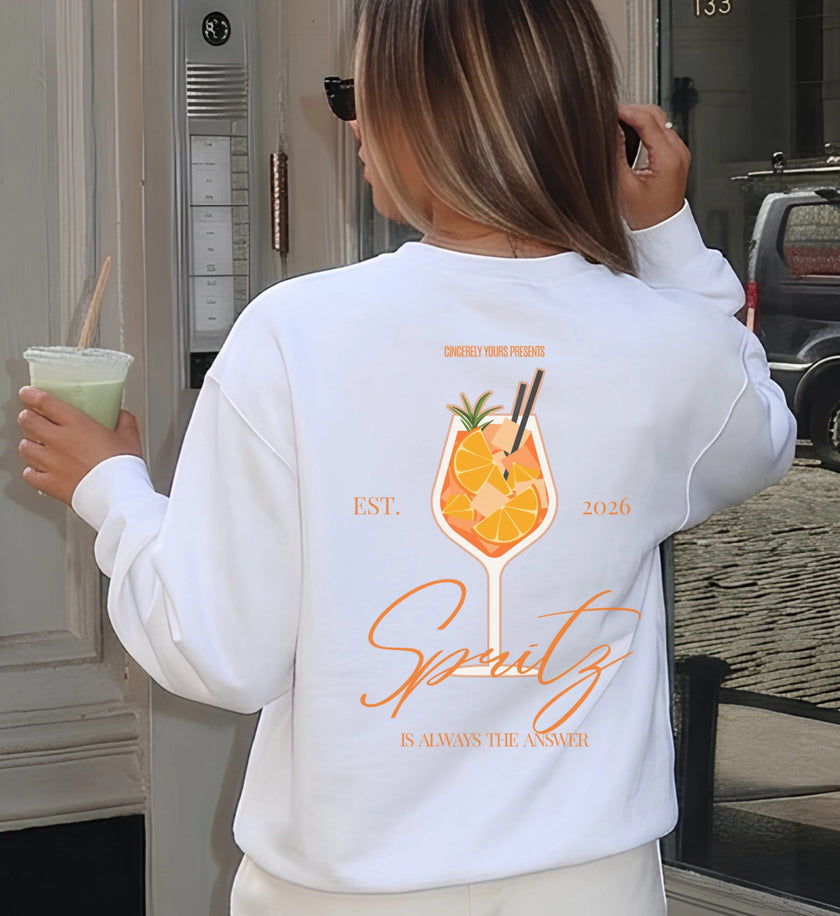 Rückenansicht eines weißen Sweatshirts mit farbenfrohem Cocktail-Grafikdruck, der einen italienischen Aperitif zeigt, kombiniert mit lässigem Alltagsoutfit.