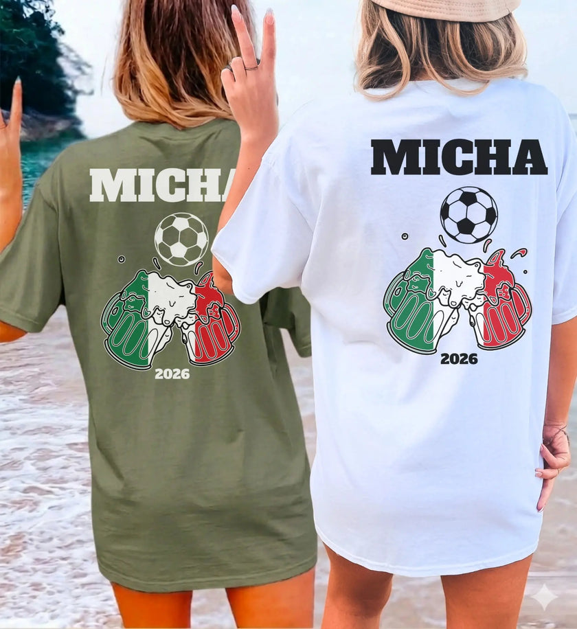 Zwei Personen am Strand tragen personalisierte T-Shirts für Italien-Fans mit einem Motiv aus anstoßenden Bierkrügen in den Nationalfarben Grün, Weiß und Rot, einem Fußball und dem Namen Micha sowie der Jahreszahl 2026.