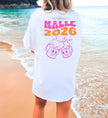 Weißes Malle T-Shirt von Cincerely Yours mit lila und orangefarbenem Malle 2026 Backprint und prostenden Bierkrügen, getragen am Strand.