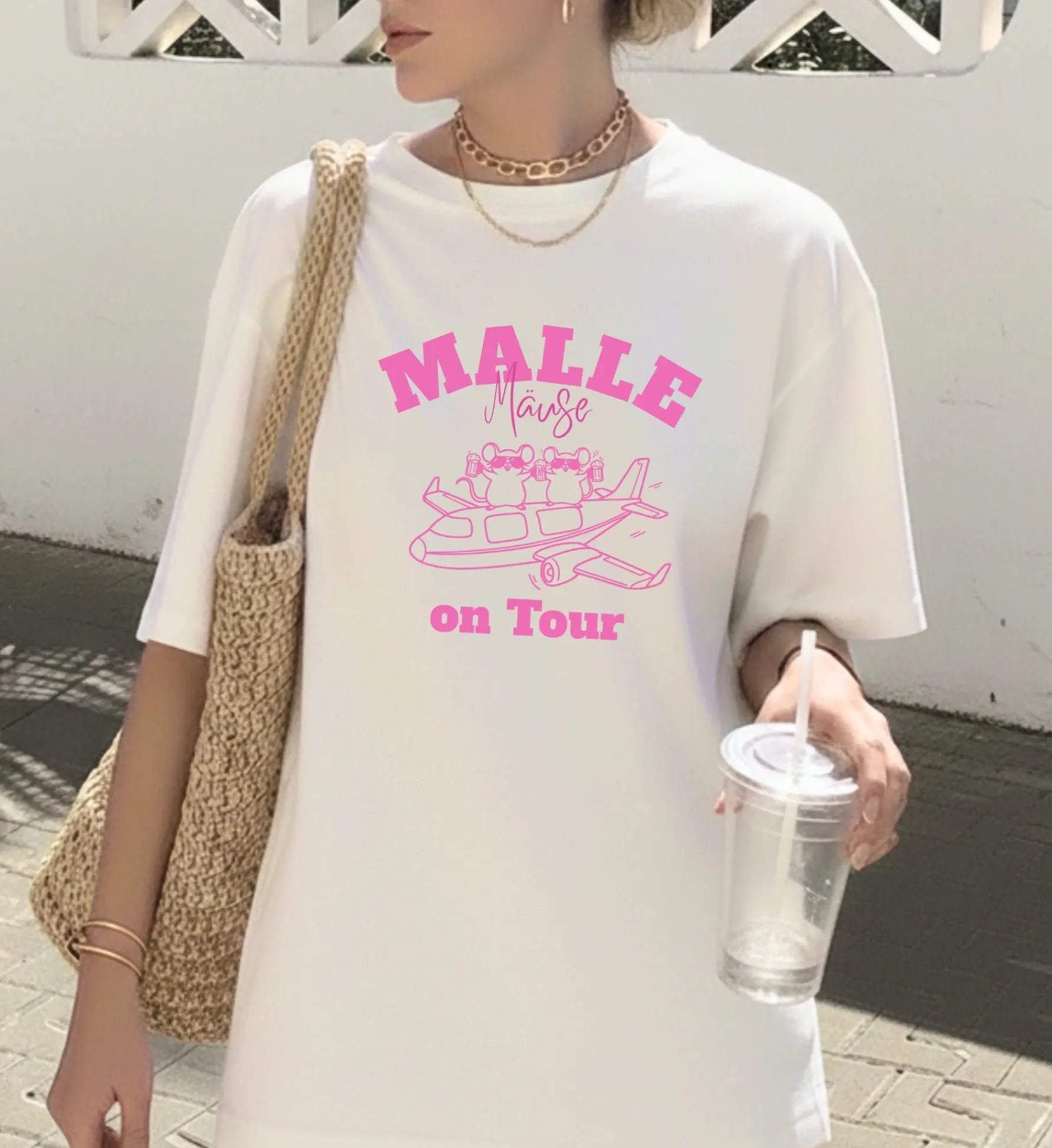 Weißes Oversized T-Shirt für Damen mit pinkem 'Malle Mäuse on Tour' Aufdruck und lustiger Mäuse-Illustration auf einem Flugzeug.