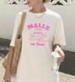 Weißes Oversized T-Shirt für Damen mit pinkem 'Malle Mäuse on Tour' Aufdruck und lustiger Mäuse-Illustration auf einem Flugzeug.