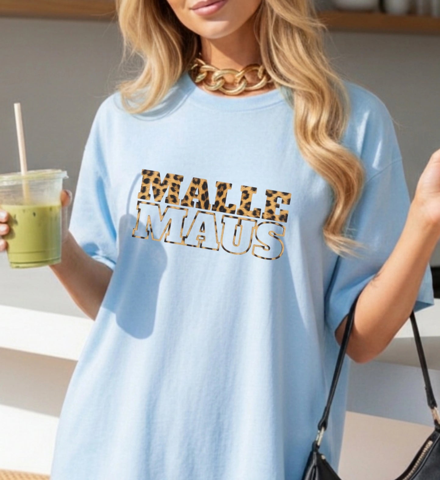 Ein hellblaues Malle Maus T-Shirt für Damen von Cincerely Yours mit einem Text-Aufdruck im Leopardenmuster, getragen von einem Model mit Smoothie.
