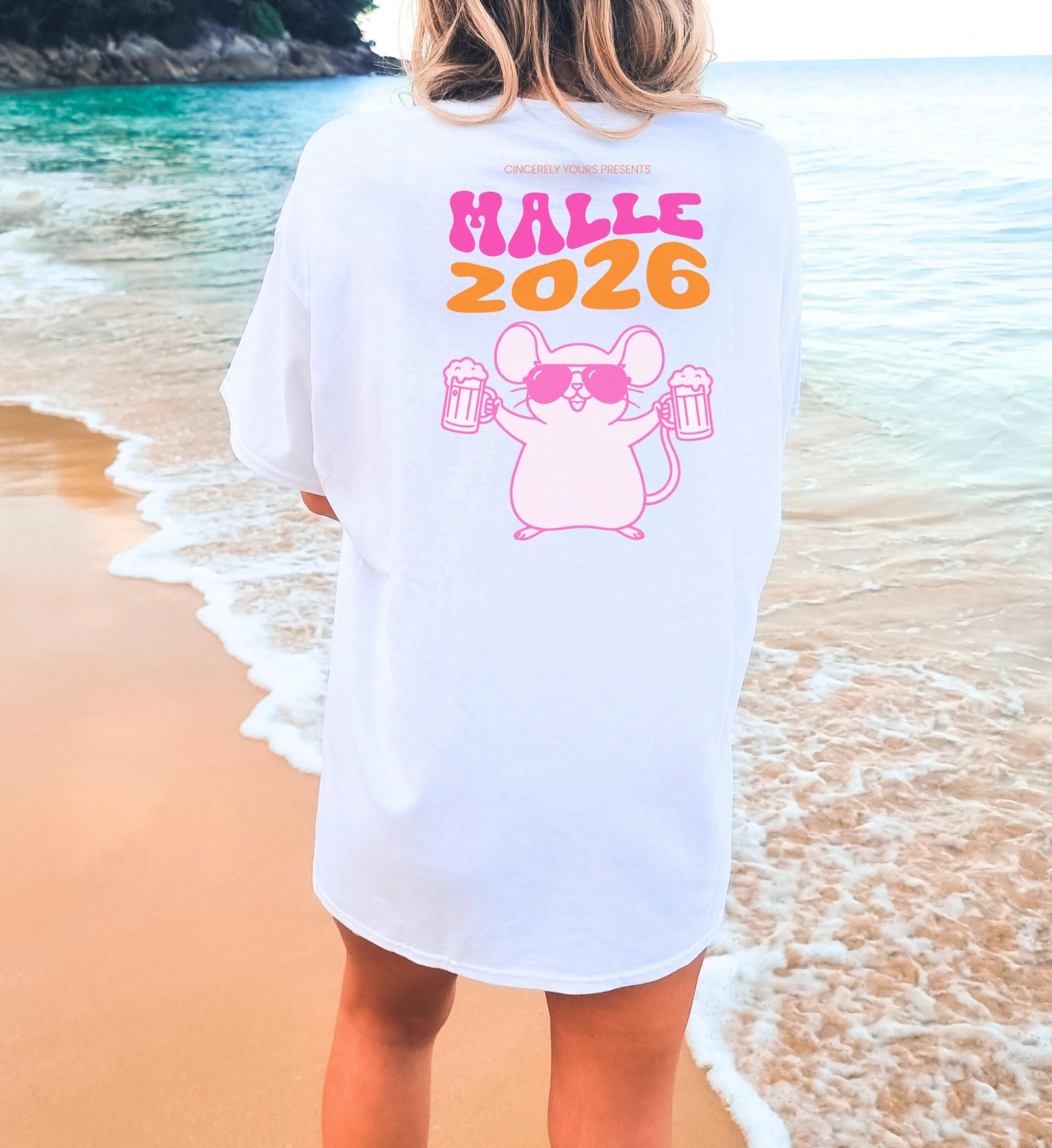 Frau trägt ein weißes Mallemaus T-Shirt von Cincerely Yours mit 'Malle 2026' Aufdruck und einer feiernden Maus mit Bierkrügen, Rückansicht am Strand.