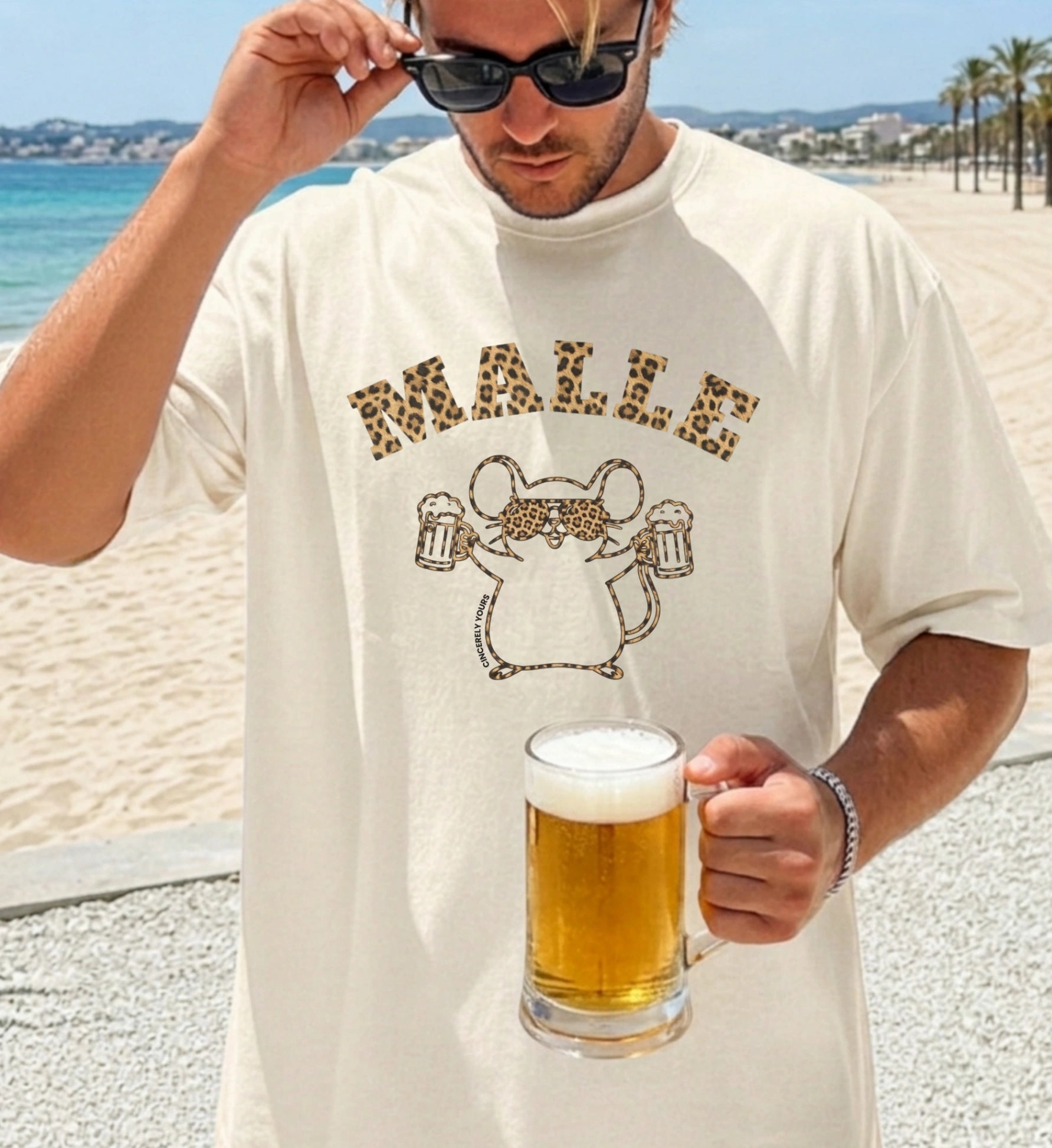 Mallemaus T-Shirt von Cincerely Yours mit Leopard-Print und Bierkrügen, getragen von einem Mann am Strand mit einem Glas Bier – das ideale Party Shirt für Malle.