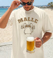 Mallemaus T-Shirt von Cincerely Yours mit Leopard-Print und Bierkrügen, getragen von einem Mann am Strand mit einem Glas Bier – das ideale Party Shirt für Malle.