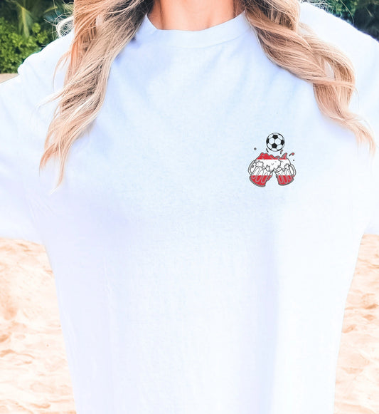 Weißes Unisex T-Shirt mit einem kleinen Brustprint, der zwei anstoßende Bierkrüge im rot-weiß-roten Österreich-Design und einen Fußball zeigt – ideal für Fußballfans und den nächsten Partyurlaub.