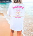 Oversized weißes JGA T-Shirt für die Braut mit pinkem Mallorca-Aufdruck, Cocktail-Grafik und Schleife am Strand.