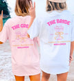 Zwei Frauen am Strand in personalisierten JGA-Shirts für die Braut und die Crew, hellrosa und weiß, mit Coquette-Design, Schleifen und Champagnerglas-Illustration für einen Junggesellinnenabschied auf Mallorca.