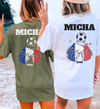 Zwei Frauen am Strand in personalisierten Fußball Fan-Shirts mit Frankreich-Bierkrug-Motiv, Fußball und Wunschnamen für die Meisterschaft 2026.