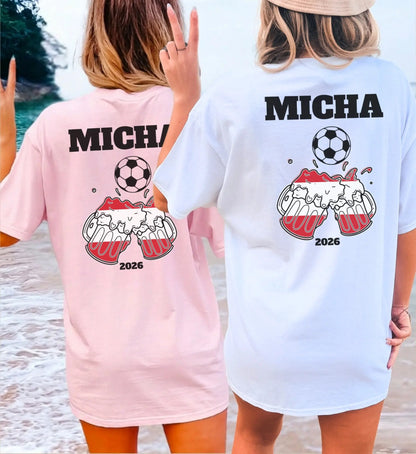 Zwei Frauen am Strand in oversized T-Shirts (Rosa und Weiß) mit personalisiertem Fußball-Design für Österreich-Fans, inklusive Wunschname, Fußball-Motiv und Bierkrügen in Landesfarben für 2026.