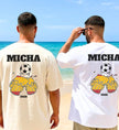Zwei Männer am Strand in personalisierten Fußball-Shirts mit individuellem Namen Micha, Fußball-Grafik und Bierkrügen in Spanien-Farben für die Meisterschaft 2026.