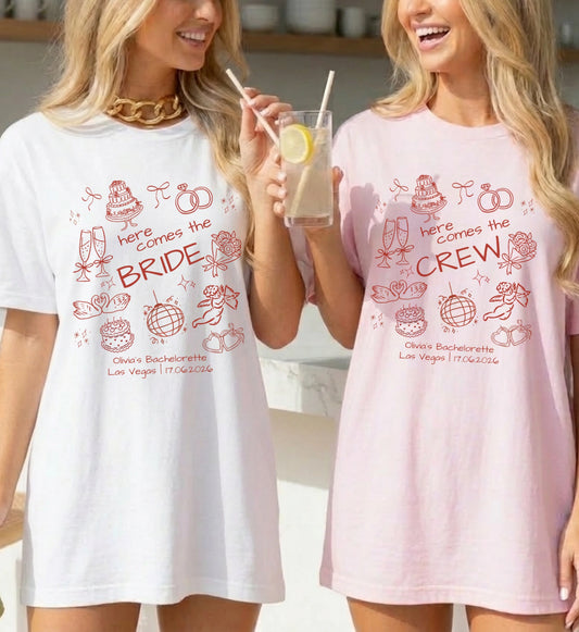 Zwei Frauen in personalisierten JGA T-Shirts in Weiß und Rosa mit handgezeichneten Doodle-Motiven 'here comes the BRIDE' und 'here comes the CREW' für den Junggesellinnenabschied.