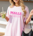 Rosa Damen Oversize T-Shirt mit pinkem 'Malle Maus' Aufdruck, getragen von einer blonden Frau mit goldener Gliederkette und grünem Smoothie.
